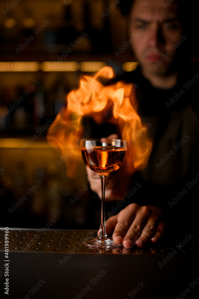 wine glass with drink stands on the bar and fiery flame is in the background