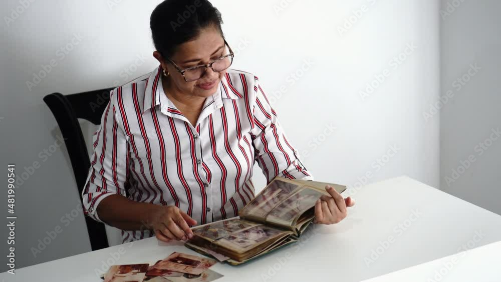 Mature woman looking at a photo album sitting in her home Mature woman looking at a photo album sitting in her home