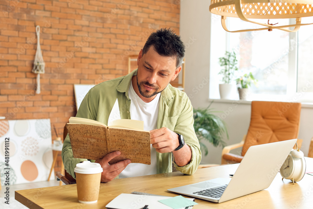 Fototapeta premium Handsome man working with notebook at table in office