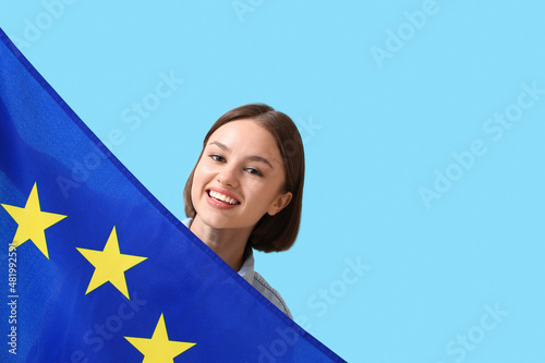 Beautiful young woman with flag of European Union on blue background