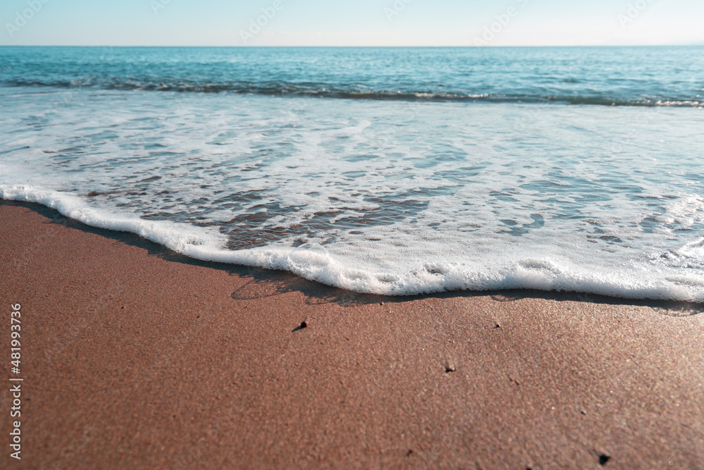 Obraz premium Smooth sandy at the beach and beautiful wave in background. Soft wave blue ocen and sandy beach. Small waves lapped the beach