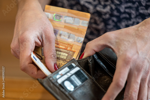 Close-up of a woman's hand putting money into a wallet