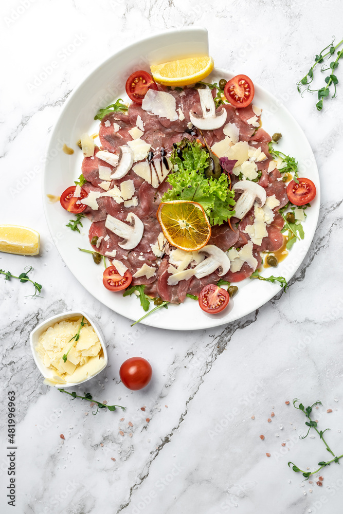 Beef carpaccio with parmesan capers and arugula. cold appetizer. italian cuisine. vertical image. top view. place for text