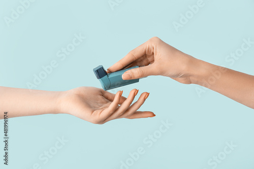 Female hands with asthma inhaler on blue background