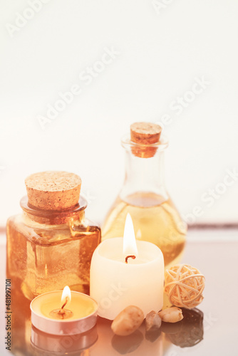 Concise spa composition with oil flasks and candles on beige background.