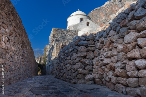 Fototapeta Naklejka Na Ścianę i Meble -  Whitewashed church against clear sky on narrow street between rough stone walls, Monemvasia, Greece