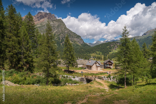 Stone house at Alpe Devero, Piedmont with trees and alps in the background