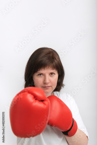 Portrait of young female boxer in red gloves on white background. Struggle for womens rights, feminism.