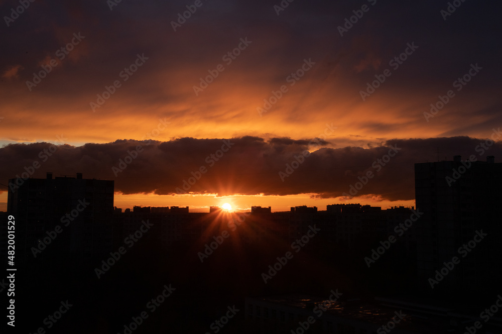 Sunset in the city of Moscow, the sun sets behind residential buildings, beautiful red clouds