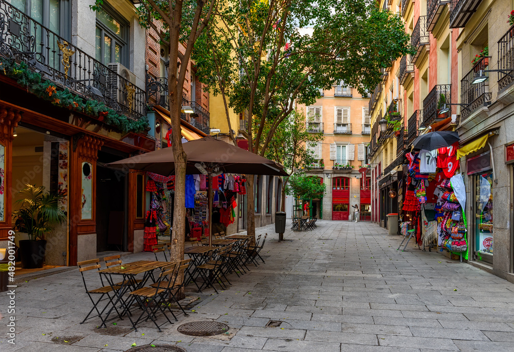 Fototapeta premium Old street with table of restaurant in Madrid, Spain. Architecture and landmark of Madrid, postcard of Madrid.