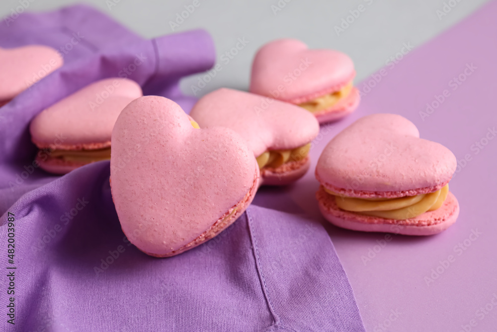 Tasty heart-shaped macaroons on purple background, closeup Tasty heart-shaped macaroons on purple background, closeup