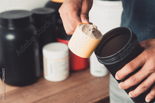 Tableau sur toile Hands holding scoop of whey protein and shaker with copy space healthy life