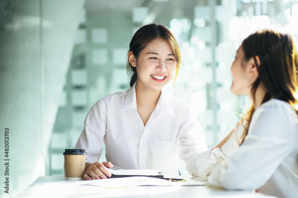 Female Asian smiles in support and puts her hand on her coworker shoulder. Female Asian smiles in support and puts her hand on her coworker shoulder.
