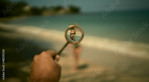 Girl on the beach. I look at the girl through a magnifying glass. Beach in the Seychelles. Tropical beach in the Indian Ocean.