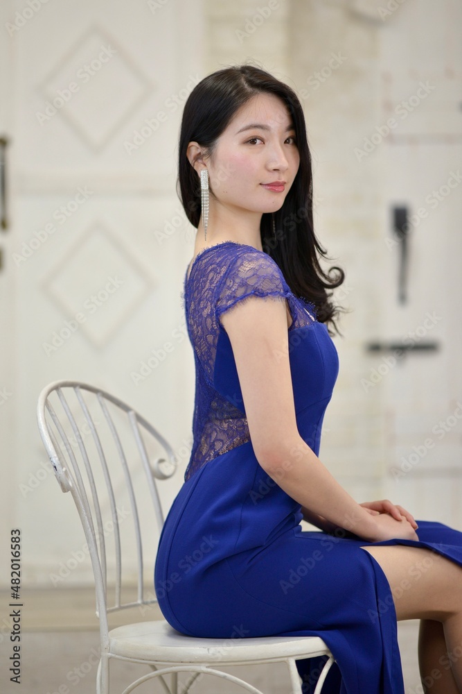 室内にて椅子に座り微笑む青いドレスを着た若く美しい女性 室内にて椅子に座り微笑む青いドレスを着た若く美しい女性
