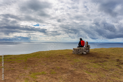 Woman on a bench looking at Leitisvatn Lake, Faroe Islands. photo