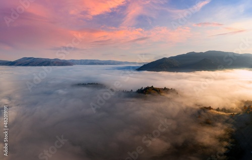 Mountains with colorful trees covered with layer of fog © YouraPechkin