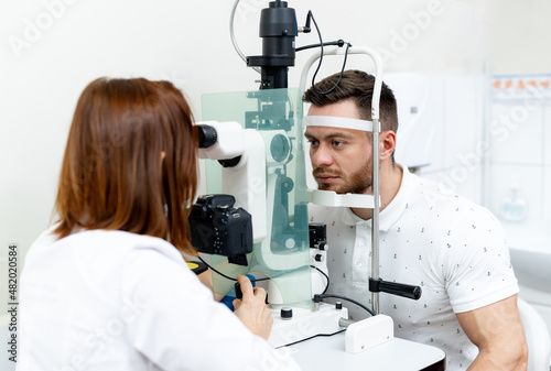 Young optometrist examining patients eyes. Optician specialist eyesight testing.