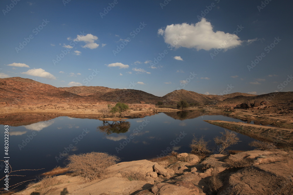 A small lake in the desert with sky reflected in the water