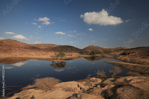 A small lake in the desert with sky reflected in the water