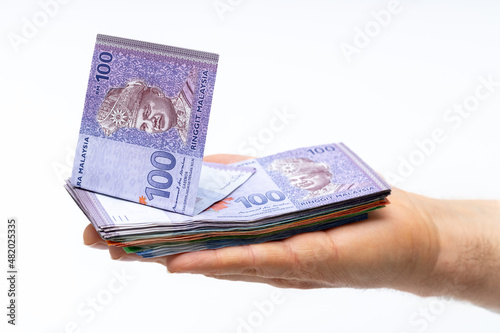 Malaysian ringits lying on an outstretched hand, Many banknotes, high value, Light background photo