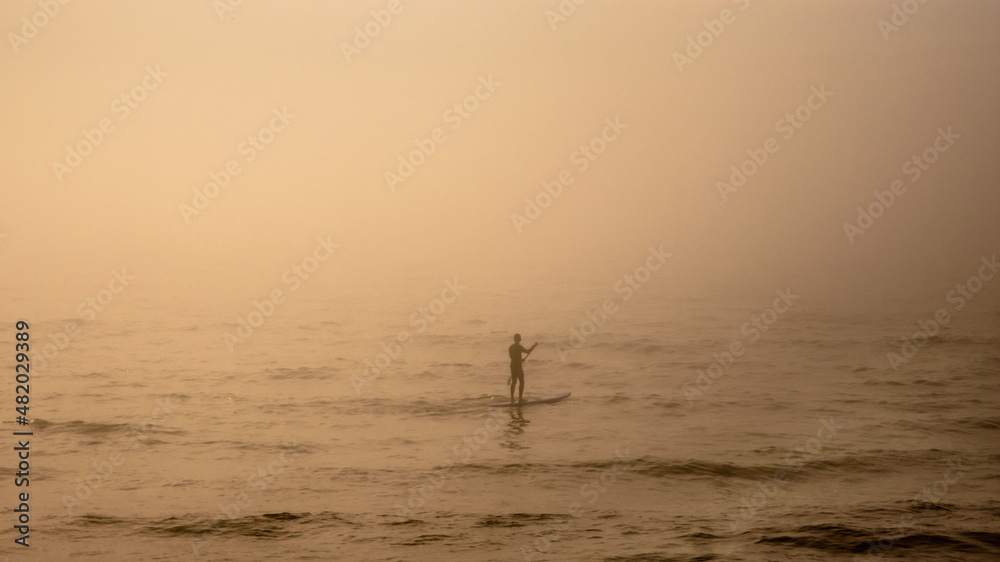 Fototapeta premium Person swimming on the water in the fog