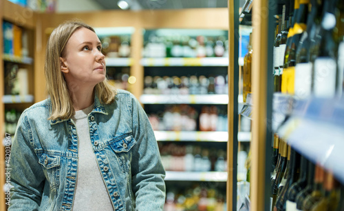 Woman choosing wine in alcohol supermarket.