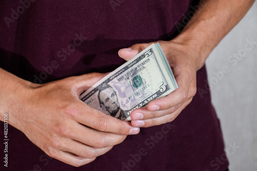 man holds a wad of dollars in his hands. US Dollars