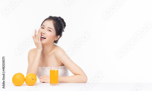 Happy young woman laughing Orange juice and orange on a table with isolated on white background and copy space Beauty asian girl love eating fruit and orange juice Health care and beauty skin concept