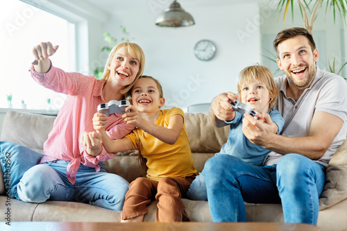 child son daughter father mother family happy playing console kid childhood joystick cotroller boy girl having fun together teamwork gaming photo