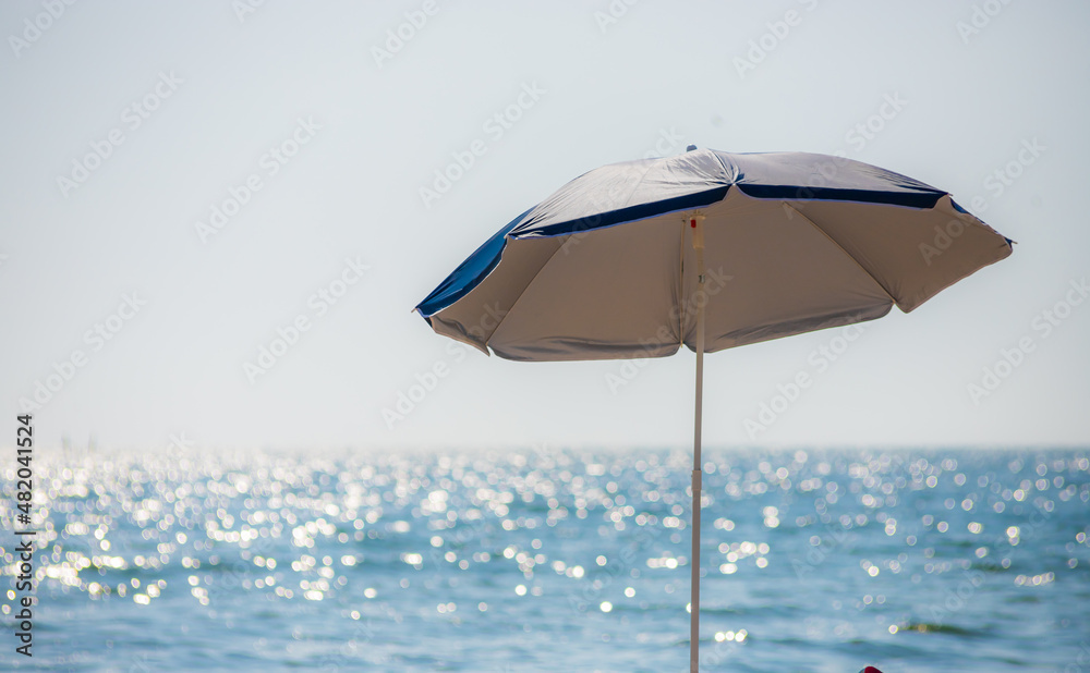 umbrella on a sandy beach with a cloudy sky, peaceful sea in background