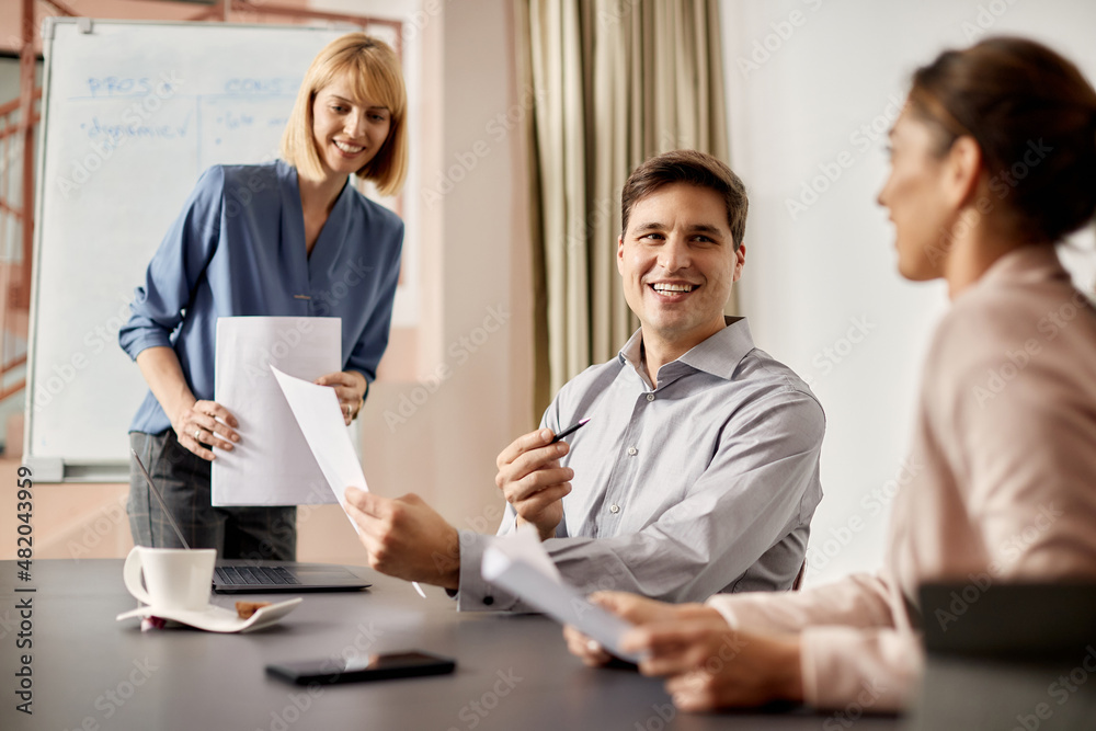 Happy businessman talks with female colleagues while analyzing reports on meeting in the office. Happy businessman talks with female colleagues while analyzing reports on meeting in the office.