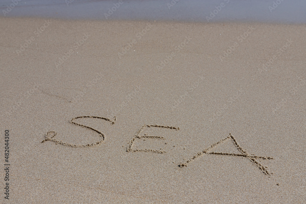 Φωτογραφία The inscription sea on the sand by the water and the rising wave, seashore beach