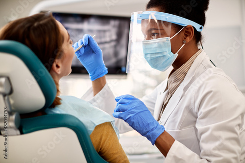 Foto Black female dentist examines woman's teeth during appointment at dental clinic