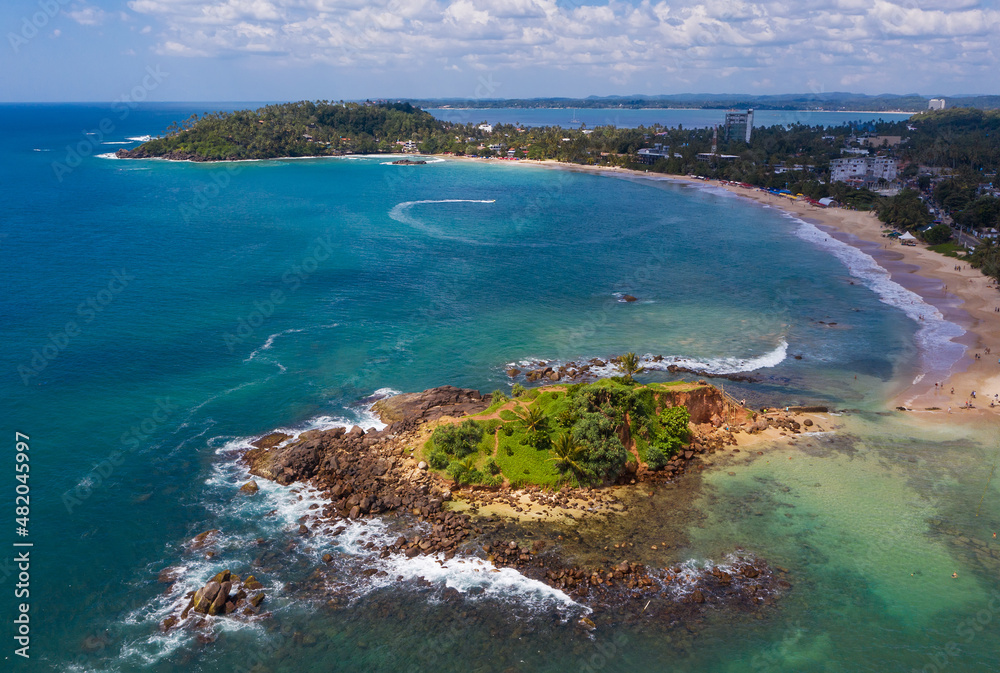 Mirissa sandy beach bay aerial photo with a Parrot Rock island beautiful Natures landmark in Matara District on Sri Lanka. Exotic Asian countries and around the World traveling concept.