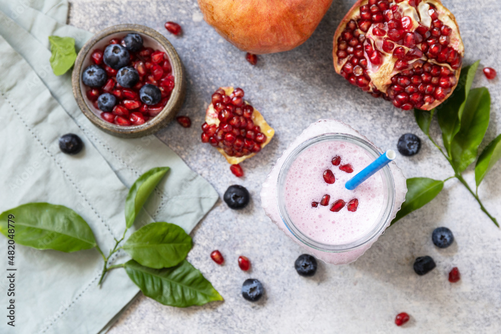 Vegan protein smoothie made from pomegranate and blueberry on a stone tabletop. Healthy food. Lifestyle wellness. Foodism, rawism, raw food diet. Top view flat lay.