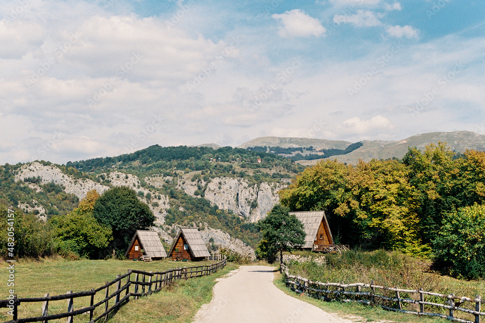 Road leading to triangular houses against the backdrop of green mountains