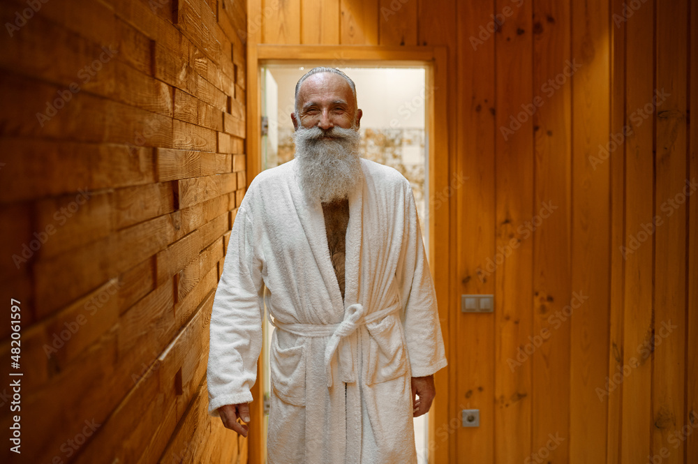 Smiling bearded man in bathrobe in sauna