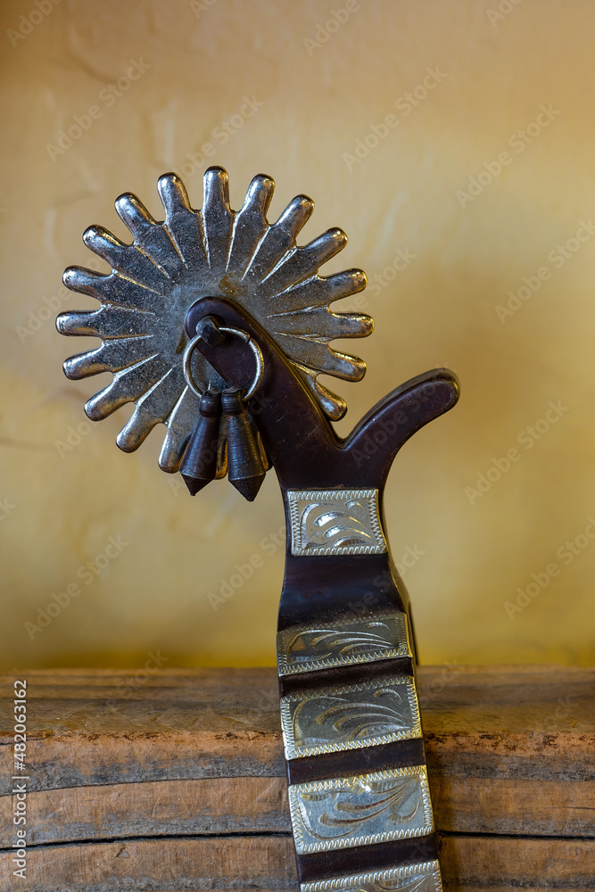 close up on the detail of a beautiful authentic western wear cowboy spur on a wooden shelf - obrazy, fototapety, plakaty 