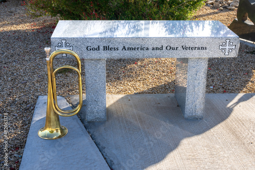 granite bench  engraved with God Gless America and Our Veterans with a brass bugle beside it photo