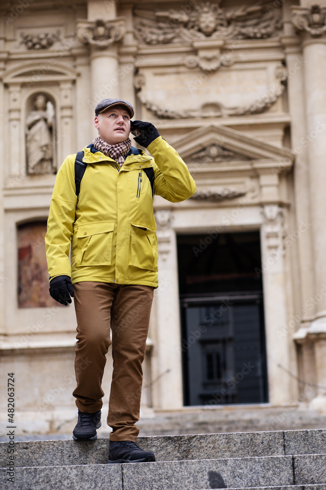 a man in a jacket walks through the beautiful streets of the city