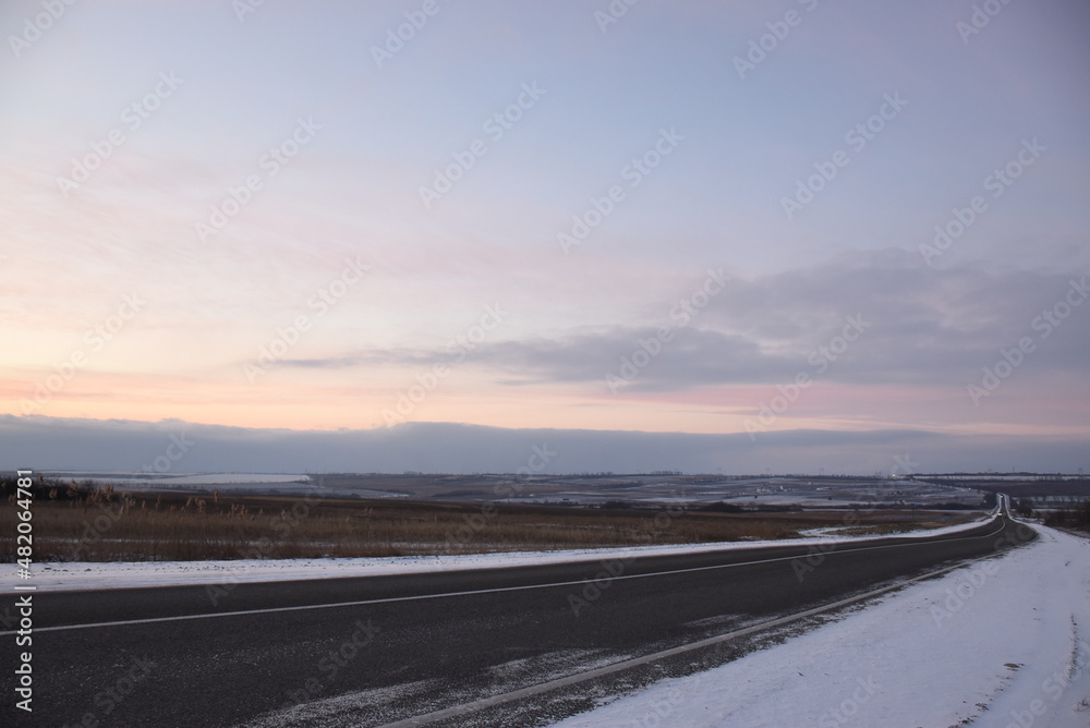 A winter snowy road runs off the horizon.