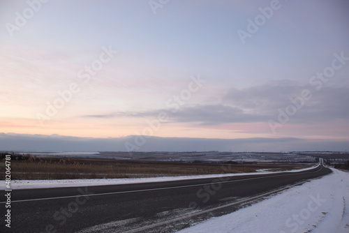 A winter snowy road runs off the horizon.
