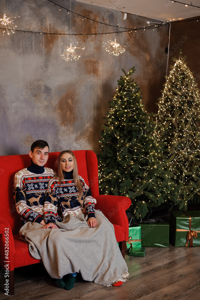Man and woman sitting on a red sofa and holding a gift