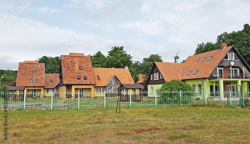 Wallpaper Mural cottage settlement behind a blue fence with orange roofs against the backdrop of a forest Torontodigital.ca