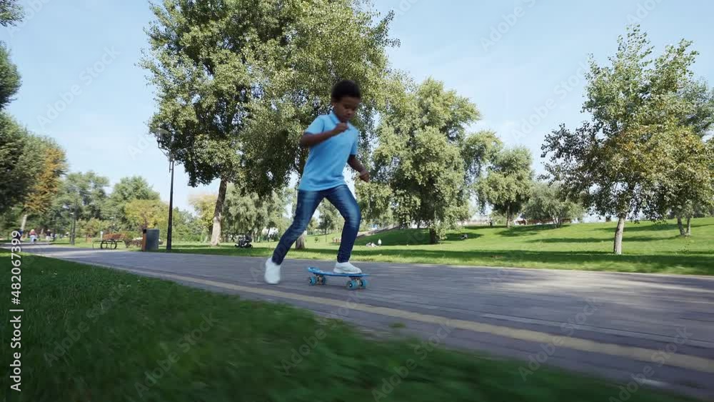 Cinematic video of a little boy traveling on his skate in a park. American child going outdoor and having fun o a beautiful sunny day. Concept about childhood and lifestyle Cinematic video of a little boy traveling on his skate in a park. American child going outdoor and having fun o a beautiful sunny day. Concept about childhood and lifestyle