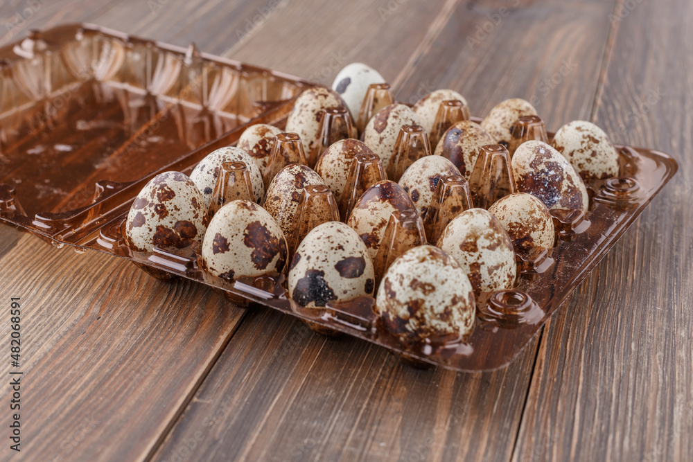 Group of quail eggs are put on clear tray on wooden table. Group of quail eggs are put on clear tray on wooden table.