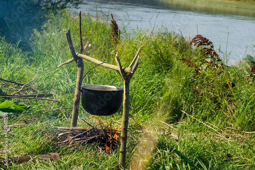 cooking porridge in a special bowl on an open fire for a group of tourists
