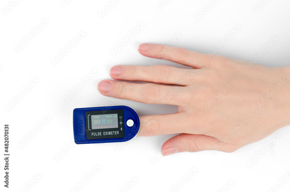 Pulse oximeter on the finger of a female hand, white background. Pulse oximeter shows saturation 99 Pulse oximeter on the finger of a female hand, white background. Pulse oximeter shows saturation 99