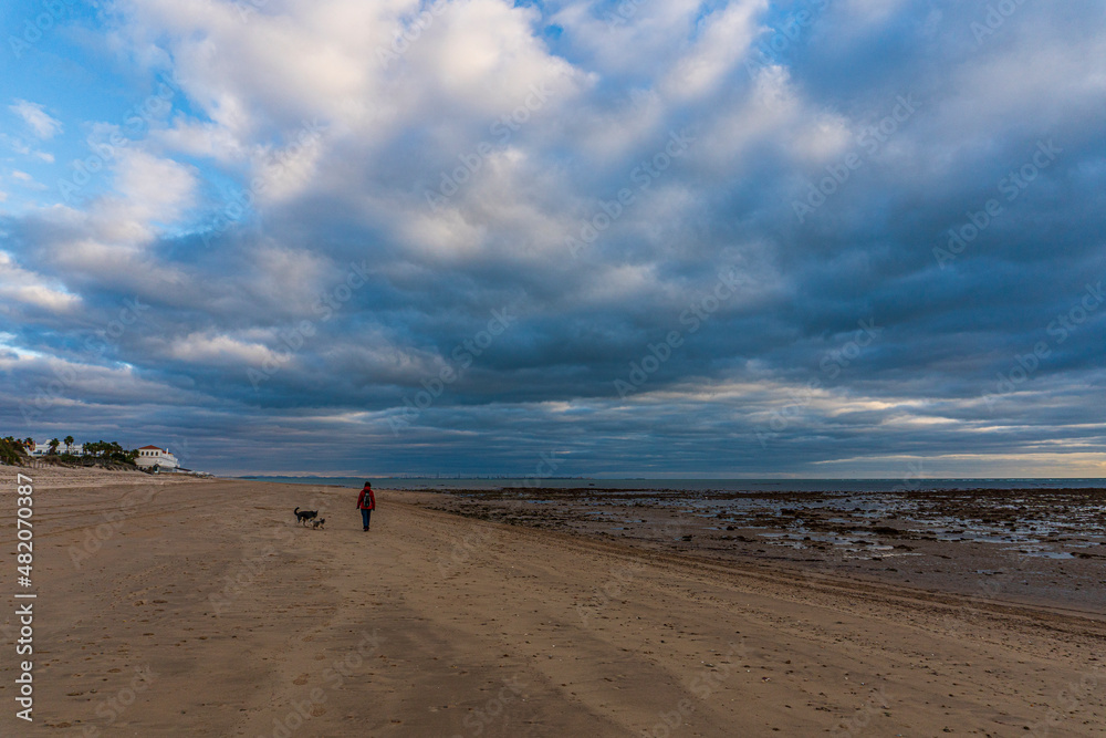 Paseo al atardecer con nubes en el cielo en la playa de Chipiona